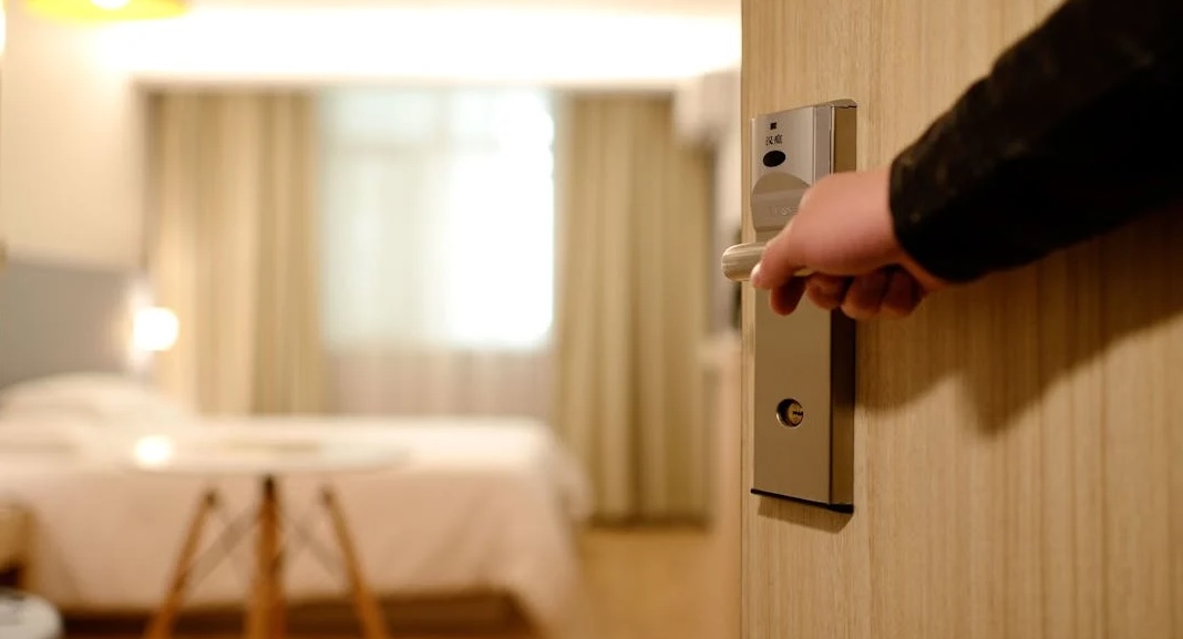 person holding open hotel room door